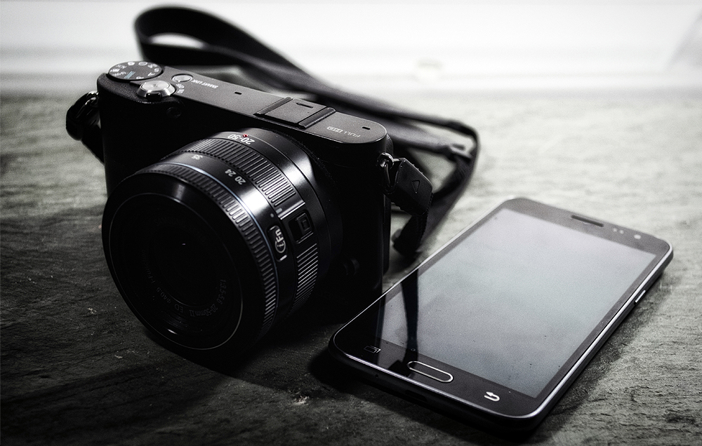 카메라와 스마트폰이 같이 놓여져있는 흑백 사진